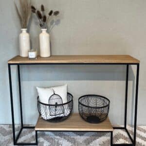 Mesa de entrada con jarrones blancos, candelabro pequeño, y cestas decorativas con cojín en la parte inferior.