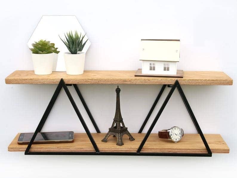 Estante de madera con decoración: miniatura de Torre Eiffel, casa, plantas, teléfono y reloj. Diseño triangular minimalista.