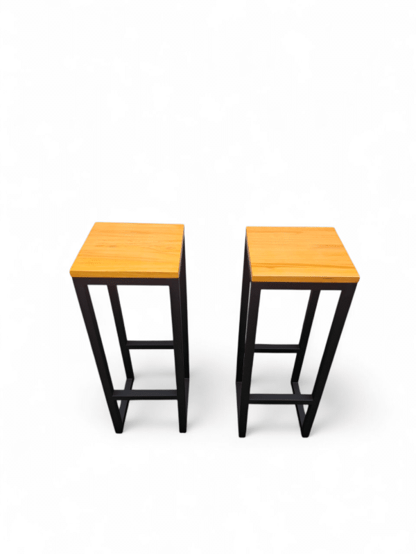 Dos taburetes altos con asiento de madera y estructura metálica negra, ideales para barras de cocina o desayunadores. Un complemento moderno y funcional para espacios contemporáneos.