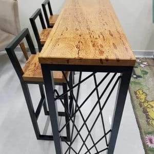 Barra alta de madera con tres sillas de respaldo cuadrado y estructura metálica. Ideal para cocina moderna o reuniones sociales en espacios pequeños. Diseño contemporáneo y funcional.