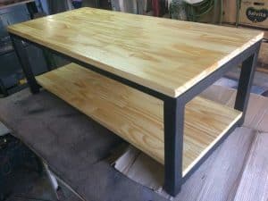 Mesa de centro estilo industrial, madera clara y estructura metálica negra. Ideal para sala de estar, combina almacenamiento y diseño moderno.