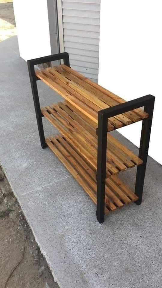 Estante de madera con estructura de metal negro para uso en exteriores. Ideal para almacenamiento de plantas o utensilios de jardín. Diseño moderno, resistente y funcional.