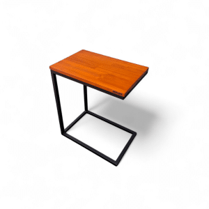 Mesa auxiliar estilo moderno con tablero de madera claro y base metálica en forma de C, ideal para usar junto a un sillón o cama. Perfecta para colocar libros, bebidas o dispositivos electrónicos.