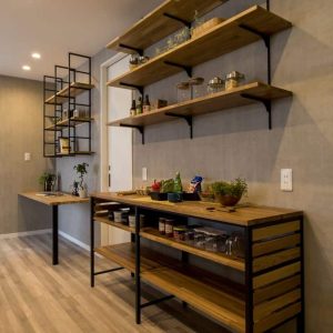 Estantería de madera con estructura metálica negra, varias repisas decoradas con frascos y plantas. Tope de mesa coordinado, diseño moderno y funcional en ambiente minimalista.