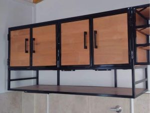 Gabinete de madera y metal negro, montado en la pared. Tiene puertas de madera con tiradores negros y estantes abiertos en un lado. Diseño moderno y funcional para almacenamiento.