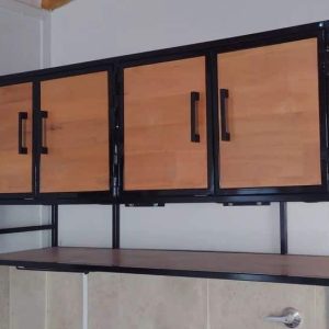 Gabinete de madera y metal negro, montado en la pared. Tiene puertas de madera con tiradores negros y estantes abiertos en un lado. Diseño moderno y funcional para almacenamiento.