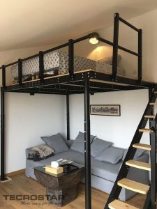 Estructura de litera alta metálica negra con cama, escalera de madera y sofá gris abajo; diseño para maximizar espacio en habitaciones pequeñas.