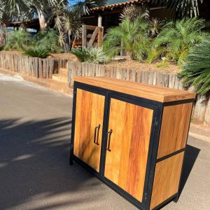 Gabinete de madera con dos puertas, marco metálico negro, mangos oscuros. Diseño moderno y rústico, ideal para exteriores o interiores con estilo industrial.