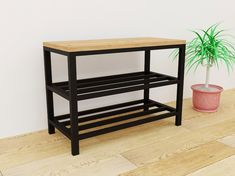 Mesa auxiliar de estructura metálica negra con tres niveles de almacenamiento. Superficie de madera clara. Diseño moderno y minimalista, ideal para interiores contemporáneos.