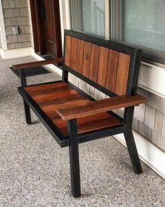 Banco de madera y metal con respaldo vertical y apoyabrazos, ideal para exteriores. Diseño rústico y robusto, perfecto para decorar patios o porches.