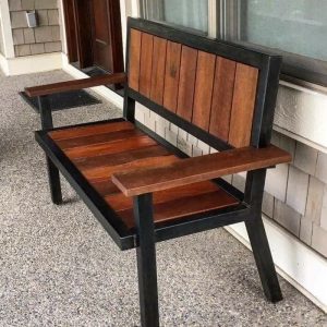 Banco de madera y metal con respaldo vertical y apoyabrazos, ideal para exteriores. Diseño rústico y robusto, perfecto para decorar patios o porches.