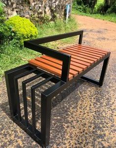 Banco moderno de jardín con asiento de listones de madera y robusta estructura metálica negra. Diseño geométrico y contemporáneo ideal para espacios exteriores.