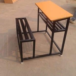 Pupitre escolar de metal con asiento integrado. La mesa es de madera con superficie lisa, color beige, y estructura de soporte robusta. Ideal para aulas o estudios.