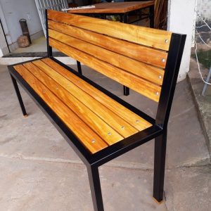 Banco de madera con estructura de metal negro, asiento y respaldo de listones de madera clara, diseño moderno y resistente. Ideal para exteriores o espacios rústicos.