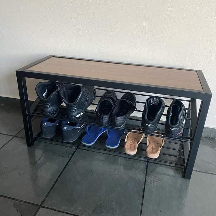 Banco zapatero negro con estructura metálica y superficie de madera, dos niveles para calzado, diseñado para optimizar espacio en la entrada del hogar.