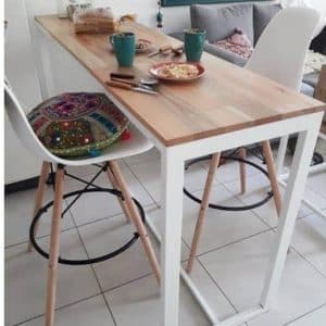Mesa alta de cocina con superficie de madera clara y estructura blanca metálica, acompañada de sillas altas de patas de madera y asiento blanco, ideal para desayunos.