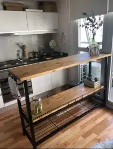 Isla de cocina de madera y metal negro, con dos estantes inferiores para almacenamiento. Diseño moderno, ideal para espacios pequeños y decoración contemporánea.