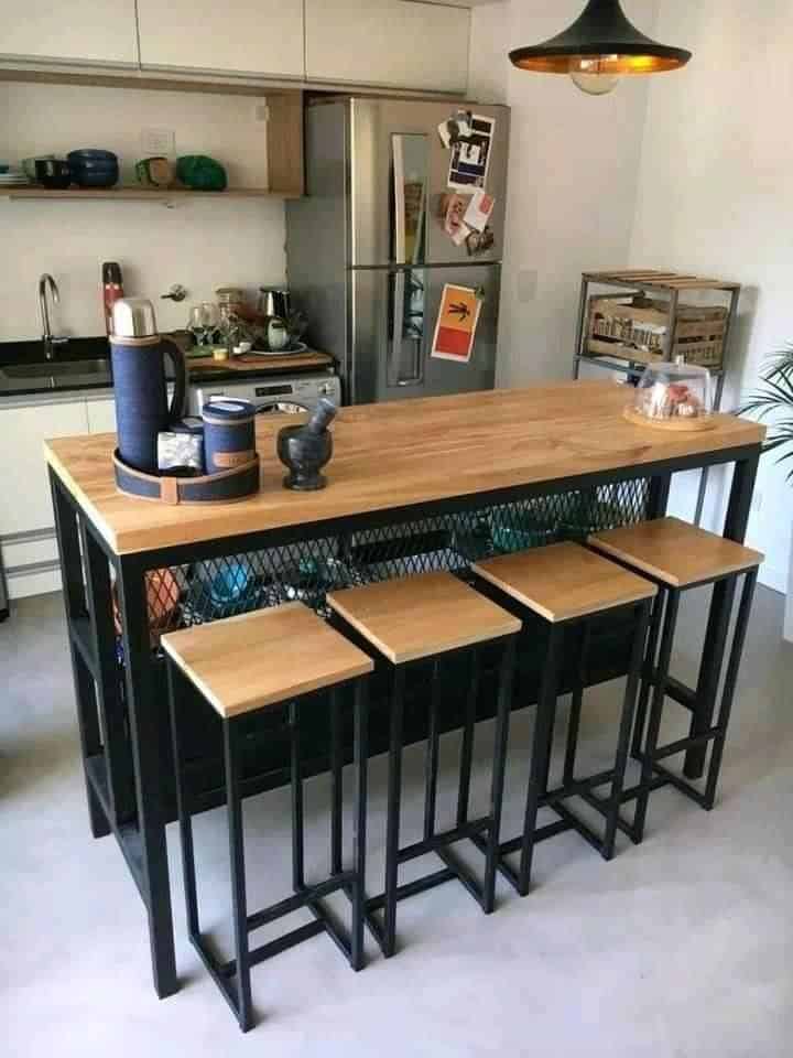 Isla de cocina con base metálica negra y tablero de madera clara. Incluye cuatro taburetes a juego, también con estructura metálica y asientos de madera. Diseño moderno e industrial.