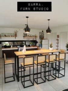 Mesa alta de madera con estructura de metal negro, rodeada de seis banquetas a juego. Diseño minimalista y moderno ideal para cocina o bar.