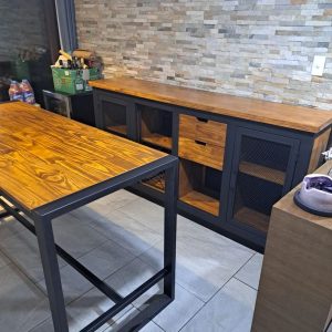 Mueble de cocina moderno con encimeras de madera y estructura negra de metal. Incluye estantes cerrados con malla y cajones de almacenamiento.