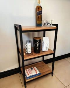 Estantería moderna de tres niveles, estructura de metal negro y estantes de madera, ideal para organización y decoración del hogar o la oficina.