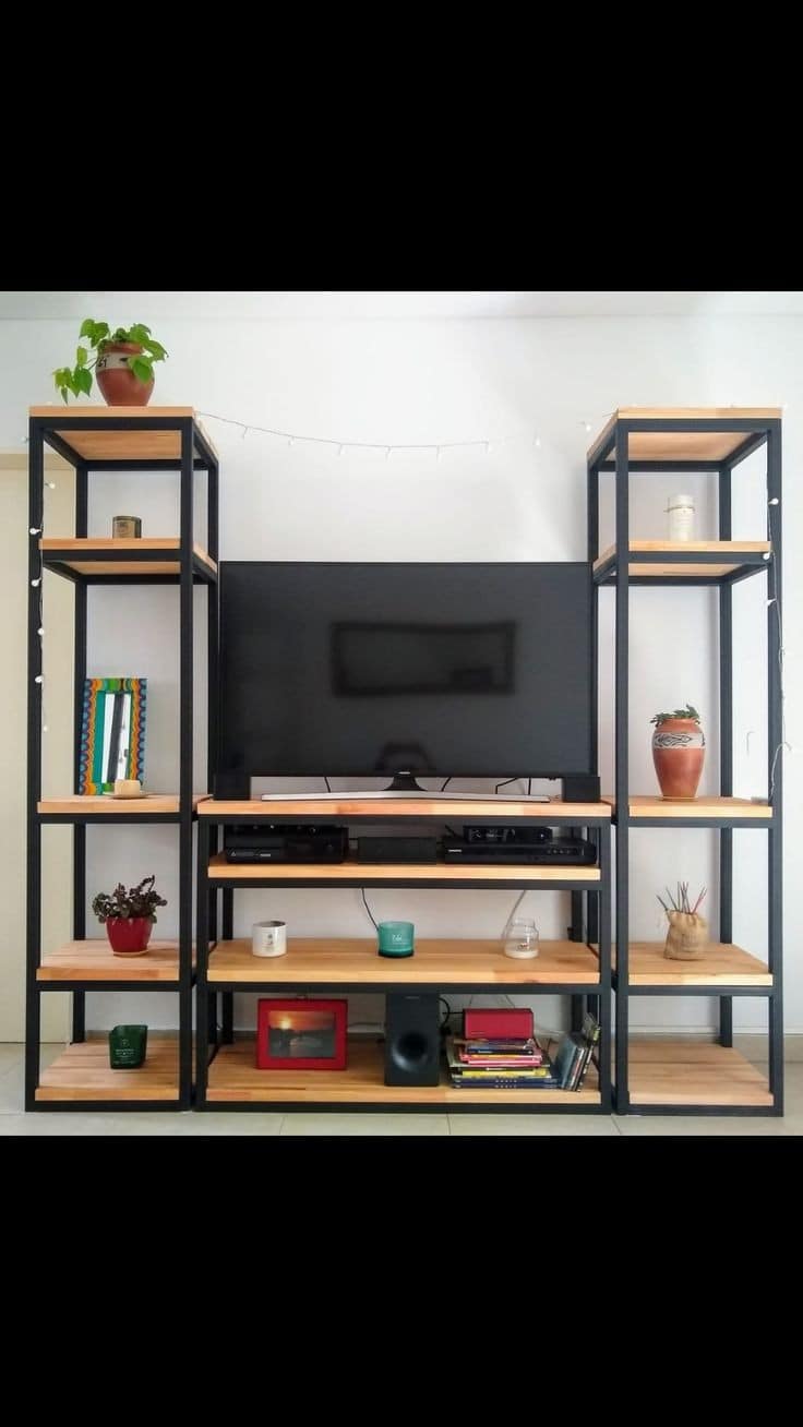 Centro de entretenimiento de madera y metal negro, con estantes abiertos. Espacio central para TV rodeado de plantas y decoración en las repisas laterales. Diseño moderno y funcional.