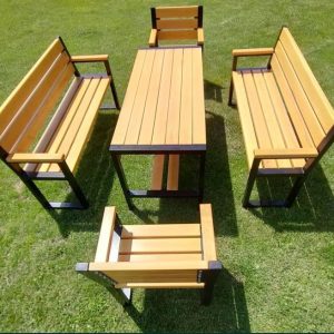 Juego de muebles de jardín con estructura de metal negro y listones de madera clara: una mesa rectangular, dos bancos con respaldo y dos sillas, ubicados sobre césped verde.