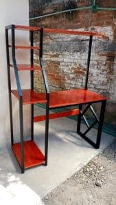 Escritorio con estantes de madera roja y estructura de metal negro. Diseño moderno y funcional, ideal para espacios de trabajo o estudio en interiores de aspecto industrial.