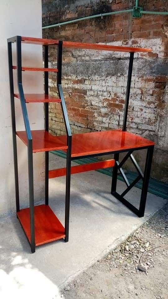 Escritorio con estantes de madera roja y estructura de metal negro. Diseño moderno y funcional, ideal para espacios de trabajo o estudio en interiores de aspecto industrial.