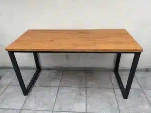 Mesa rectangular con superficie de madera clara y patas de metal negro en estructura de diseño industrial. Ideal para oficinas o comedores modernos.