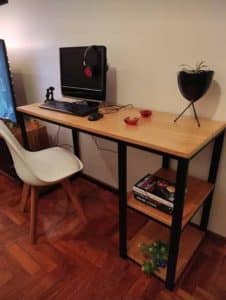 Escritorio de madera minimalista con estructura de metal negro, dos niveles con estantes abiertos a la derecha. Ideal para espacios de trabajo modernos y organizados.