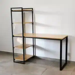 Escritorio esquinero de estilo industrial con estructura metálica negra y superficies de madera clara. Incluye estantería lateral con cuatro baldas. Ideal para oficina o estudio.