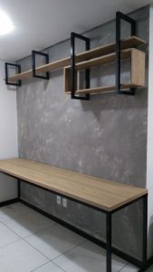 Escritorio moderno de madera clara con estructura de metal negro. Cuenta con estantes flotantes en la pared, de diseño minimalista y contemporáneo, ideal para espacios de trabajo.