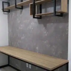 Escritorio moderno de madera clara con estructura de metal negro. Cuenta con estantes flotantes en la pared, de diseño minimalista y contemporáneo, ideal para espacios de trabajo.