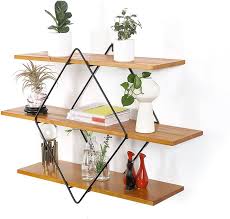 Estante de pared de madera con tres niveles, sostenido por estructura de metal en forma de rombo, decorado con plantas y objetos pequeños. Ideal para decoración moderna y minimalista.