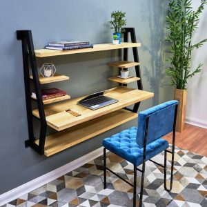 Escritorio flotante de madera con estructura metálica negra, estantes asimétricos para libros y decoración, ideal para oficina en casa, acompañado de una silla acolchada azul.