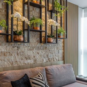 Estantes modernos de metal negro montados en una pared de piedra, adornados con macetas y plantas decorativas, combinando funcionalidad y diseño contemporáneo.
