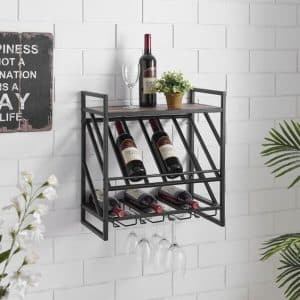 Estante de metal negro montado en pared para botellas de vino, con espacio para copas colgantes y planta decorativa en la parte superior, sobre fondo de paredes blancas de azulejos.