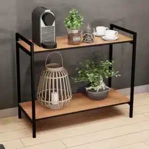 Estantería de madera con estructura metálica negra, de dos niveles. Arriba contiene una cafetera y tazas; abajo, una lámpara decorativa de mimbre y una planta en maceta.