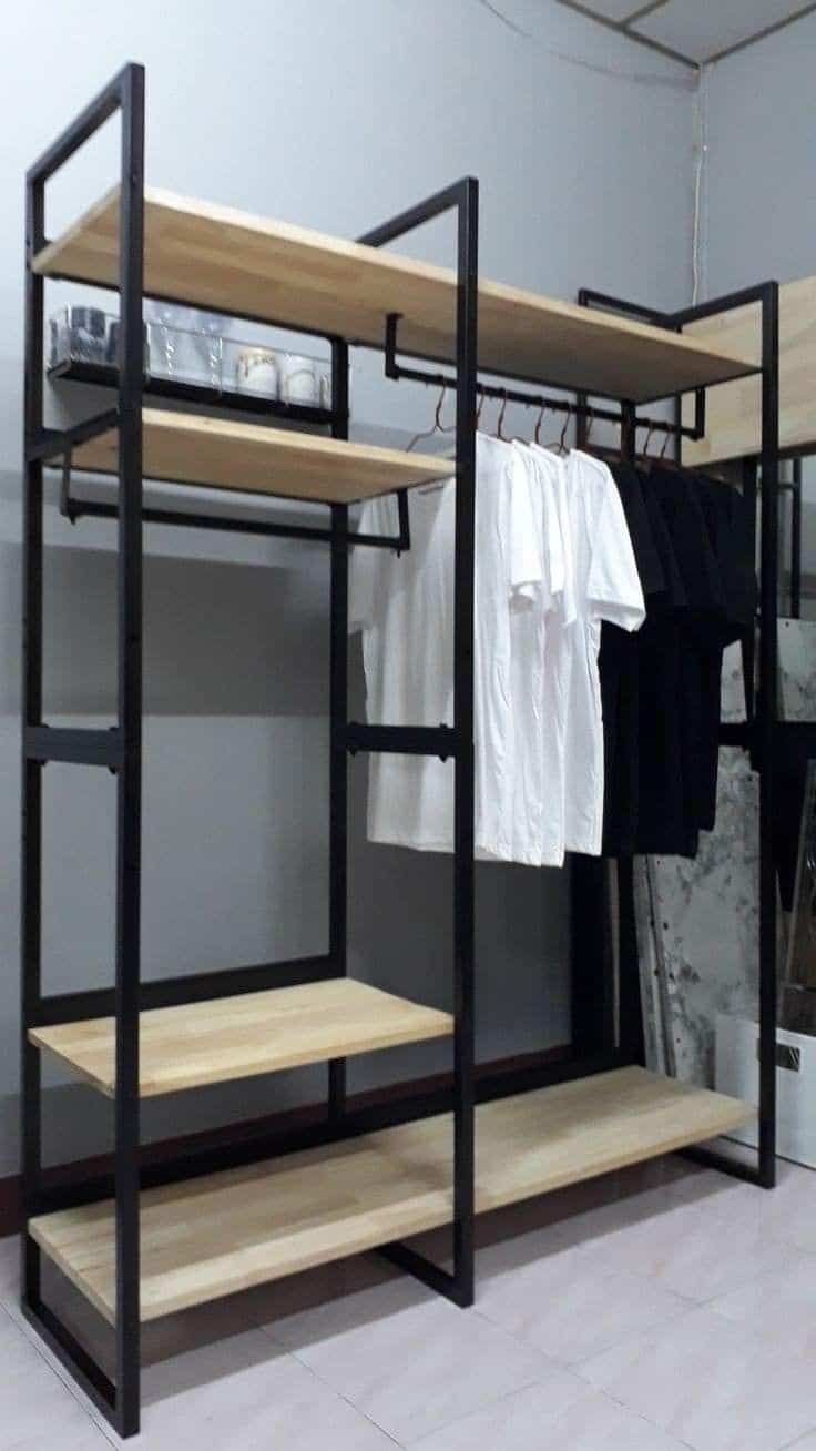 Estante de metal negro con baldas de madera clara, incluye barra para colgar ropa. Diseño moderno, ideal para organizar espacios en casa o tienda.