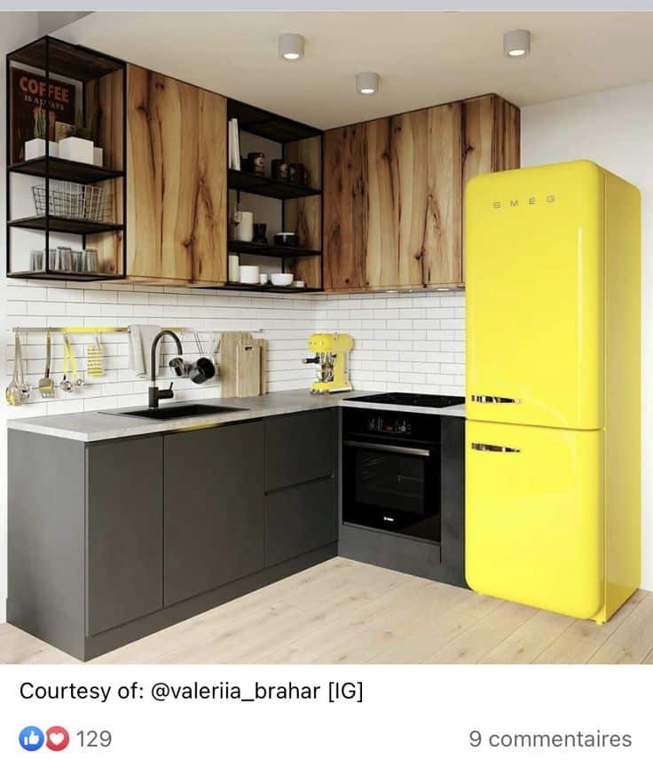 Cocina moderna con gabinetes de madera rústica, encimeras grises, y un refrigerador amarillo vintage. Electrodomésticos en negro y detalles metálicos completan el diseño.