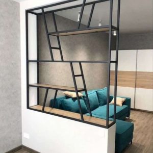 Estantería moderna de metal negro integrada en la pared, con diseño asimétrico y estantes de madera, ideal para separar espacios y exhibir objetos decorativos.