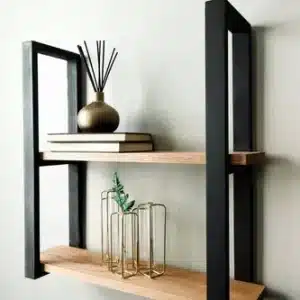 Estante de pared moderno de madera clara con soporte metálico negro. Tiene dos baldas y está decorado con libros y elementos decorativos. Estilo minimalista.