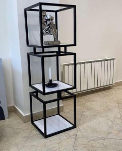 Estantería moderna de tres niveles con estructura cuadrada de metal negro y estantes blancos, perfecta para decoración contemporánea.