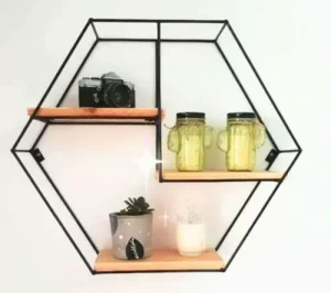 Estante hexagonal de metal negro con tres repisas de madera, decorado con cámara, tazas de vidrio y planta. Diseño moderno para organización y decoración del hogar.