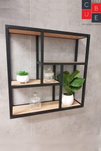 Estante de pared con marco de metal negro y baldas de madera, diseño geométrico moderno. Incluye decoración minimalista con plantas y frascos de vidrio.