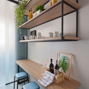 Estantes flotantes de madera con soportes negros, sobre barra de madera con taburetes, ideal para cocina moderna.