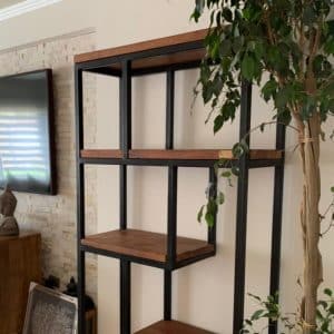 Estantería moderna de madera y metal negro, con varios estantes cuadrados, ubicada en una sala de estar con un diseño elegante y minimalista.