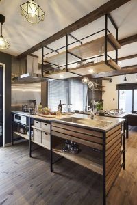 Isla de cocina moderna con estructura de metal negro y madera. Incluye fregadero de acero inoxidable, estantes abiertos y cajones integrados, ideal para un estilo industrial elegante.