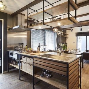 Isla de cocina moderna con estructura de metal negro y madera. Incluye fregadero de acero inoxidable, estantes abiertos y cajones integrados, ideal para un estilo industrial elegante.